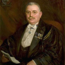 Portrait of Dr. Themistocles Zammit (1864-1935) painted by Edward Caruana Dingli against a dark red background, with the University crest in the upper left corner