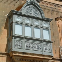 Wooden balcony decorated with lace-like wrought iron