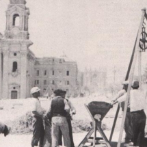 Workmen pulling and measuring grain from the underground granaries in front of the bombed St Publius church, Floriana, after it was hit on April 28